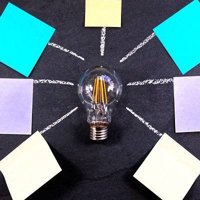 Light bulb with sticky notes on blackboard