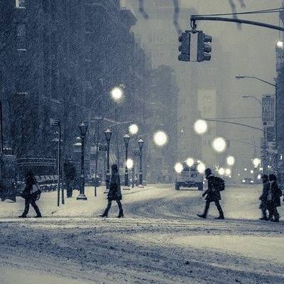 Pedestrians crossing snowy city street at night